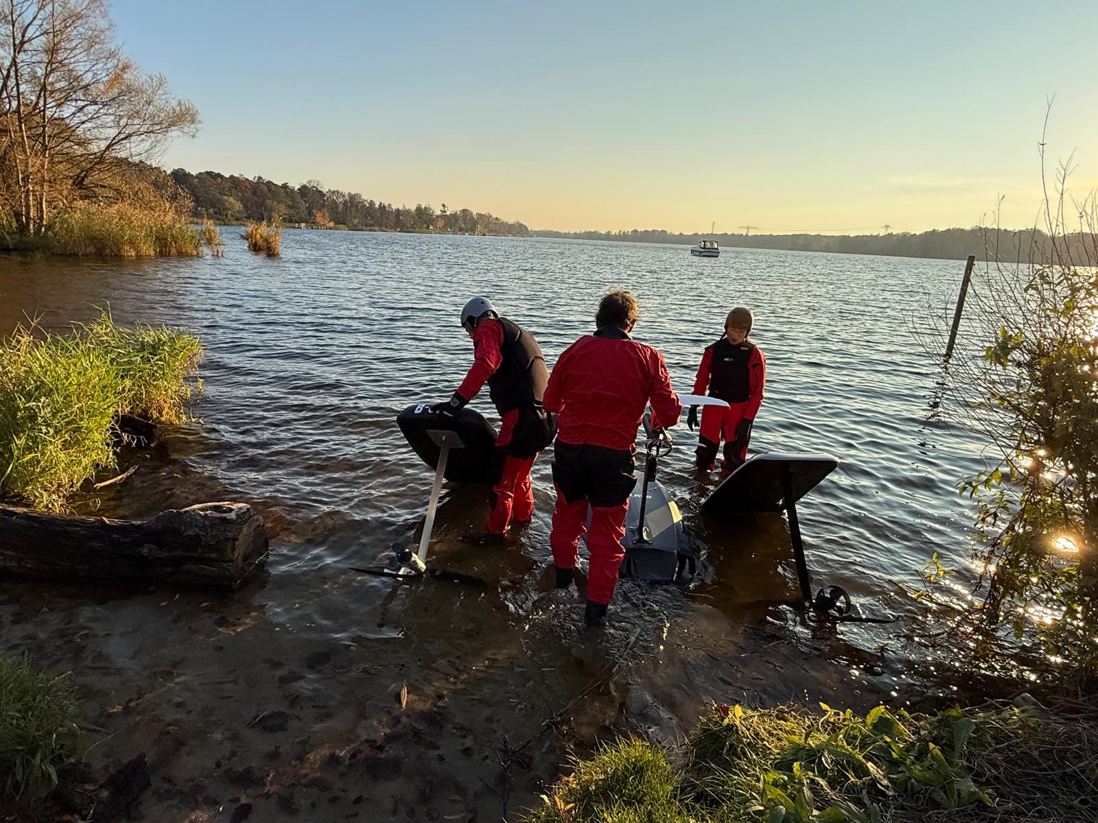 Team trägt eFoil Boards ins Wasser bei Sonnenuntergang